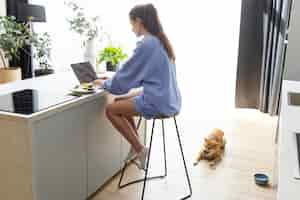 Free photo young woman working on her laptop next to her dog