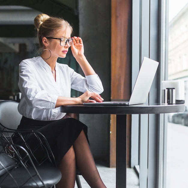 Young woman working on laptop in restaurant