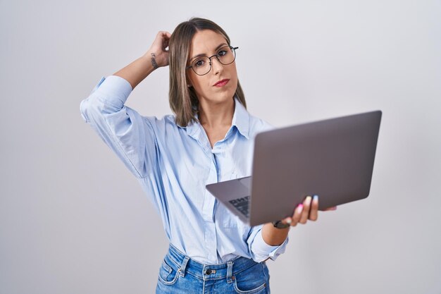 Young woman working using computer laptop confuse and wondering about question. uncertain with doubt, thinking with hand on head. pensive concept.