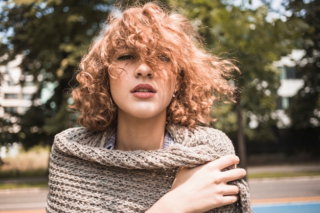 Free photo young woman wrapping in scarf in park