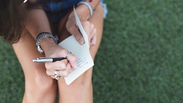 Young woman writing message on paper with pen