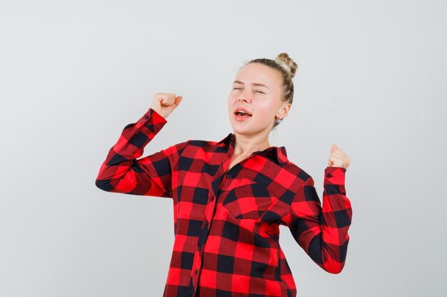 Free photo young woman yawning and stretching in checked shirt and looking relaxed