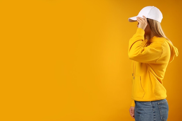 Free photo a young woman in a yellow hooded sweatshirt and cap