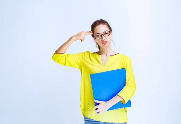 Young woman in yellow shirt looks thoughtful and dreamy