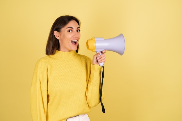 Free Photo young woman in yellow warm sweater with megaphone speaker excited and screaming