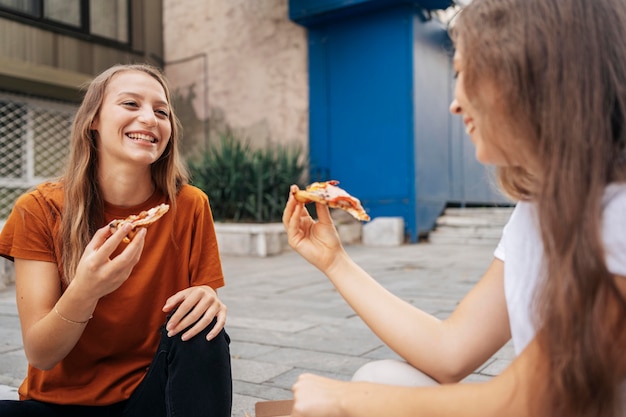 Young women eating pizza together