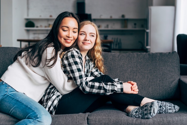 Young women embracing on sofa