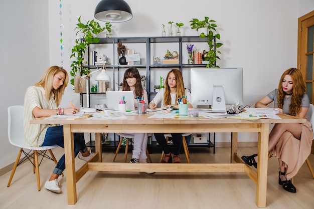 Young women gathering at table creating