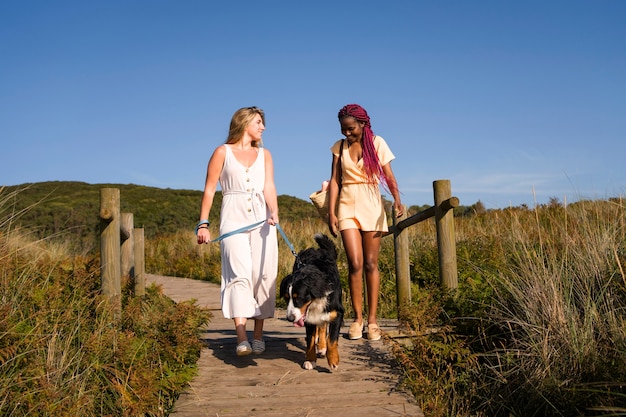 Free photo young women having fun with  dog at the beach