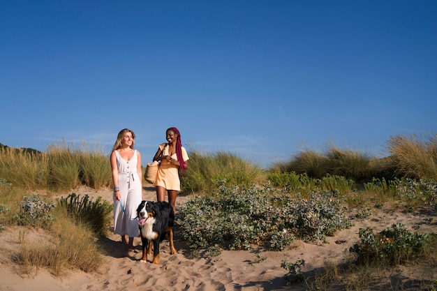 Free photo young women having fun with  dog at the beach