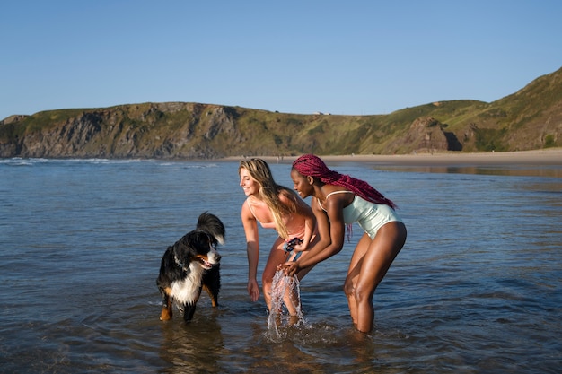 Free photo young women having fun with  dog at the beach