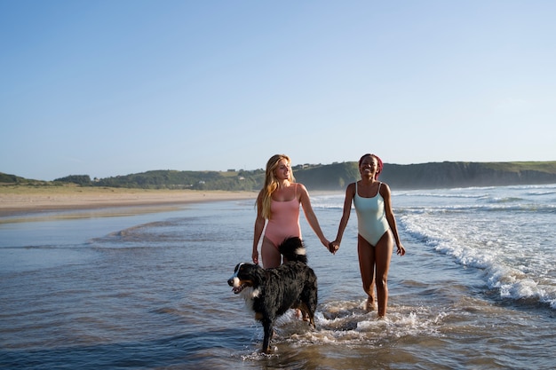 Free photo young women having fun with  dog at the beach