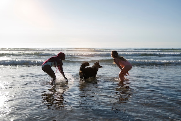 Free photo young women having fun with  dog at the beach