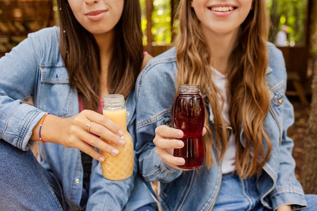 Free photo young women holding fresh juice bottles