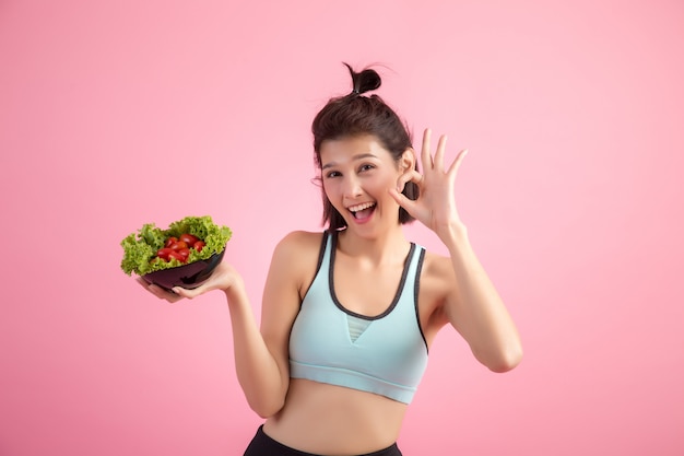 Young women like to eat vegetables on a pink.