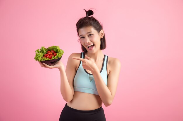 Young women like to eat vegetables on a pink.