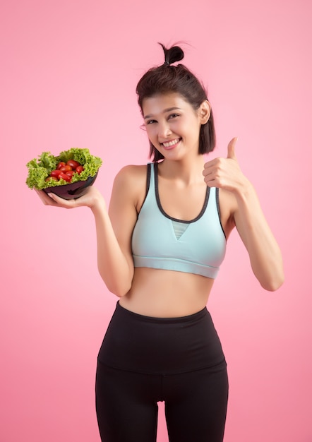 Young women like to eat vegetables on a pink.