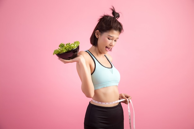 Young women like to eat vegetables on a pink.