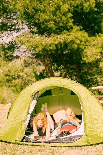 Free photo young women reading books in tent