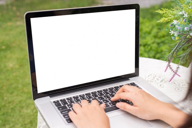 Young women using laptop computer on table at garden . view side. mock up screen free space for your design