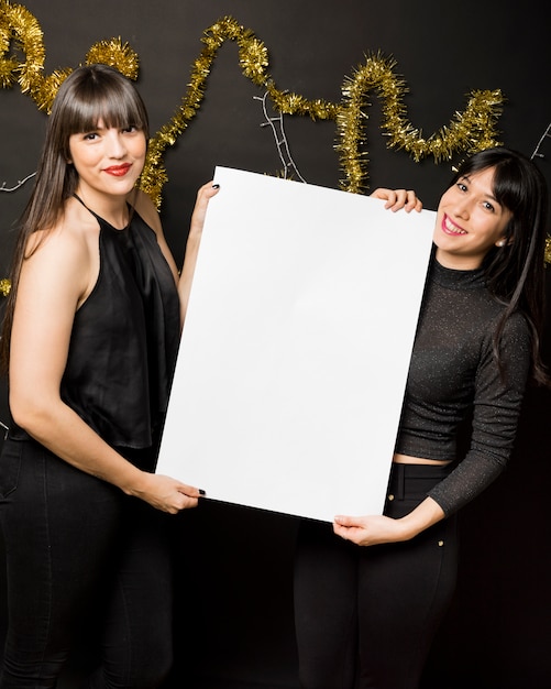 Free Photo young women with canvas near tinsel 