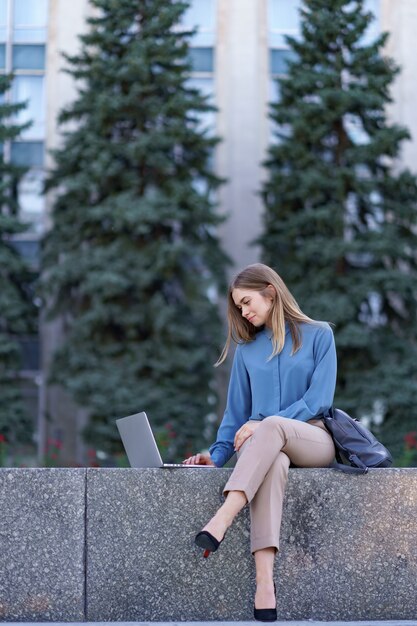 Young women working on laptop in the city square