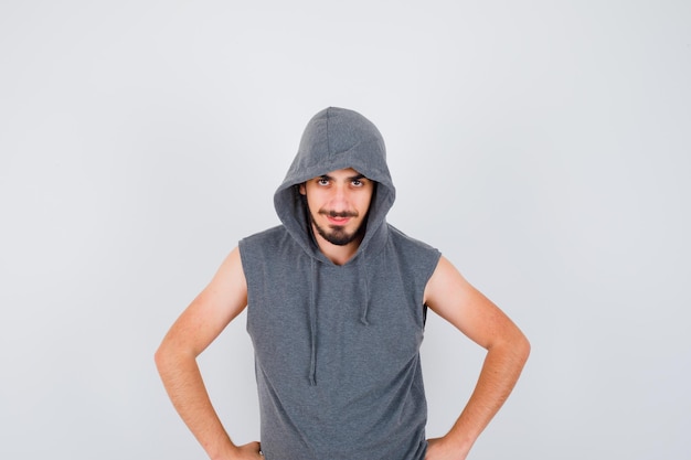 Free Photo young worker in gray t-shirt and cap holding hands on waist and looking happy