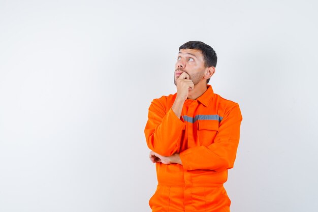 Young worker looking up in uniform and looking pensive.