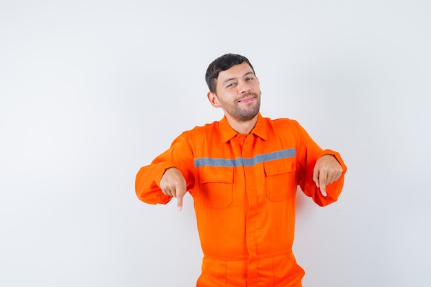 Young worker pointing down in uniform and looking cheery.