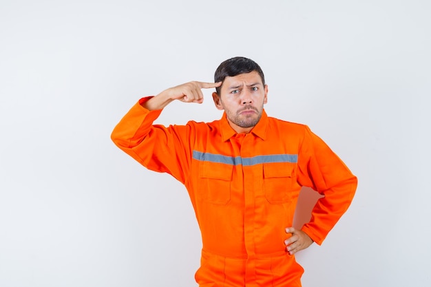 Young worker pointing finger to temples in uniform and looking nervous.