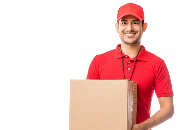 Young worker smiling while carrying parcel over white background