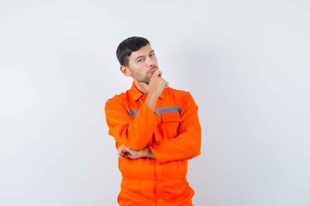 Young worker standing in thinking pose in uniform and looking confident.