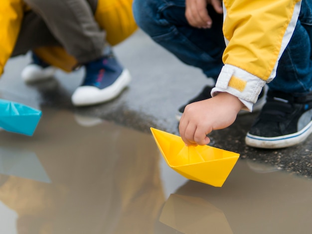 Free photo youngsters in raincoats playing with plastic boats