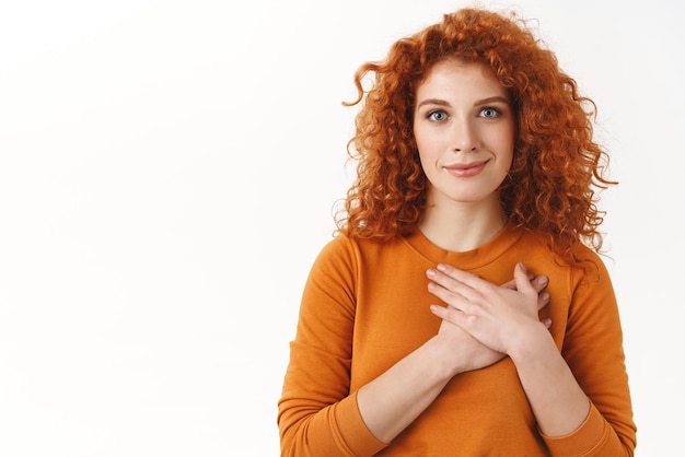 Free photo your support mean a lot touched tender gorgeous redhead woman with blue eyes curly haircut press hands to heart grateful smiling pleased thankful for nice gift appreciate help white background