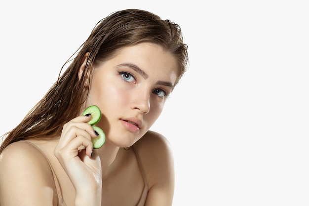 Youth secrets. Close up of beautiful young woman with cucumber on white background.