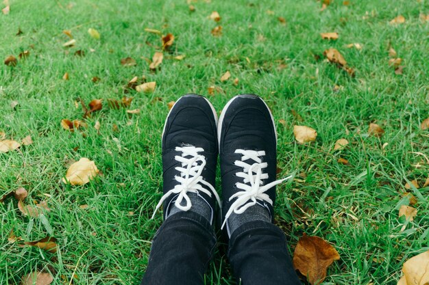 youth sneakers on girl legs on grass during sunny serene summer day.