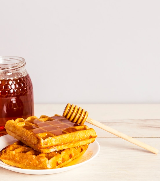 Free photo yummy baked waffle with delicious honey on white plate