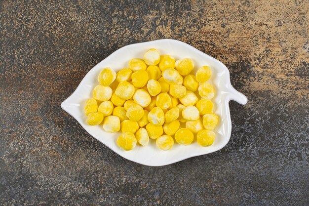 Yummy yellow candies on leaf shaped plate. 