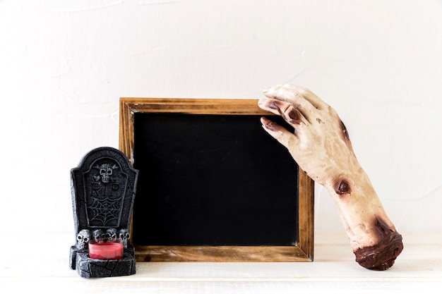 Zombie hand and gravestone near blackboard