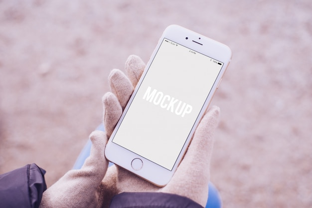 Hands with gloves holding a smartphone mock up