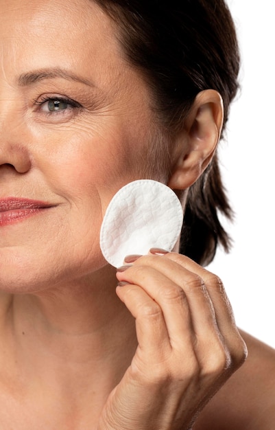 Portrait of senior woman with cotton pad for skin cleaning