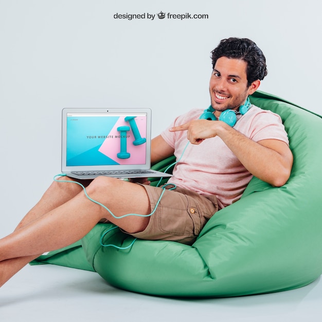 Free PSD smiley young guy pointing laptop's mock up