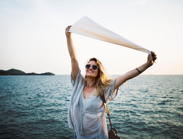 Woman in front of sea holding flag