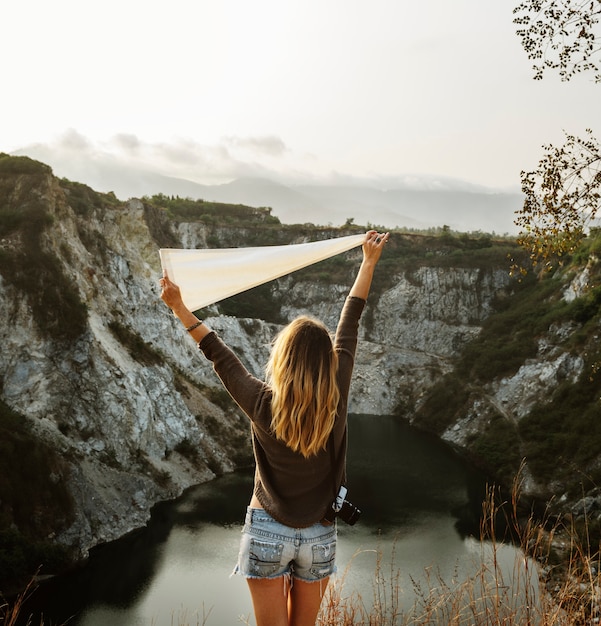 Woman with arms raised and holding flag on mountain