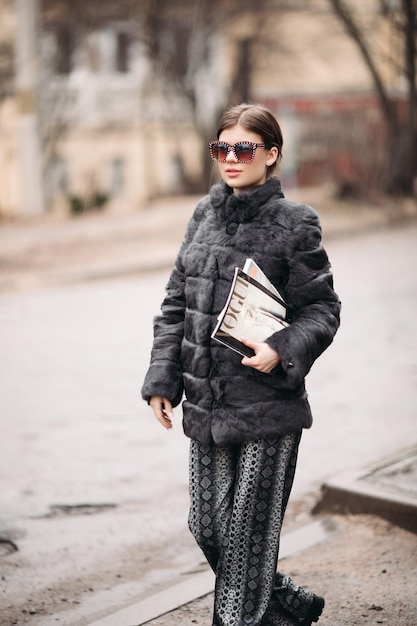 03 18 2019 Belarus Minsk Trendy woman in fur coat and sunglasses posing on street