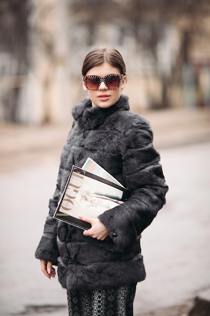 03 18 2019 Belarus Minsk Trendy woman in fur coat and sunglasses posing on street