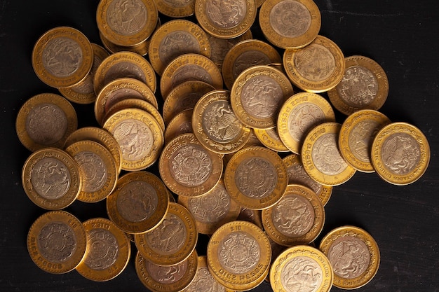 10 mexican peso coins on black background