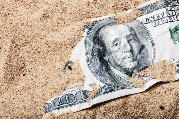 100 dollar bill buried in the sand