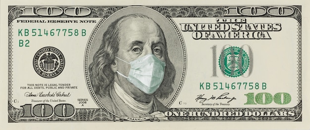 Photo 100-dollar bill with a face mask by benjamin franklin from the covid-19 coronavirus in the united states.