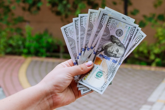 100 - dollar bills in the hands of a woman.